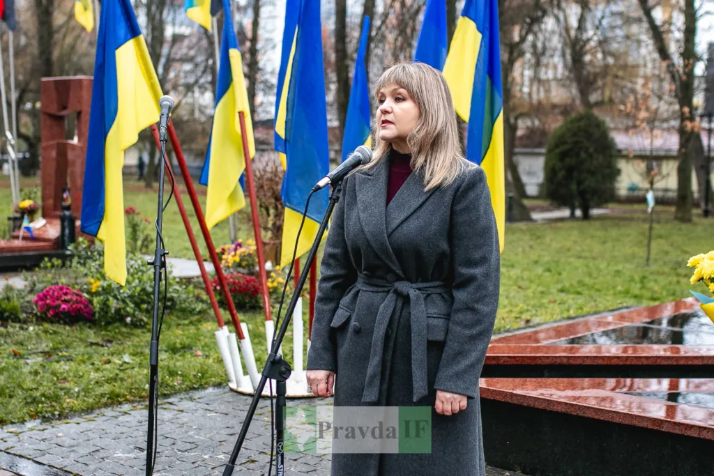 Жінка виступає біля українських прапорів на вулиці
