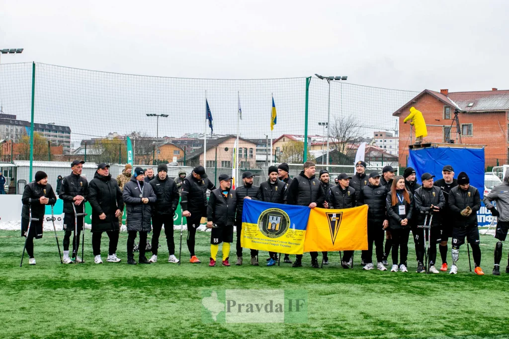 Футбольна команда ветеранів тримає прапор на полі