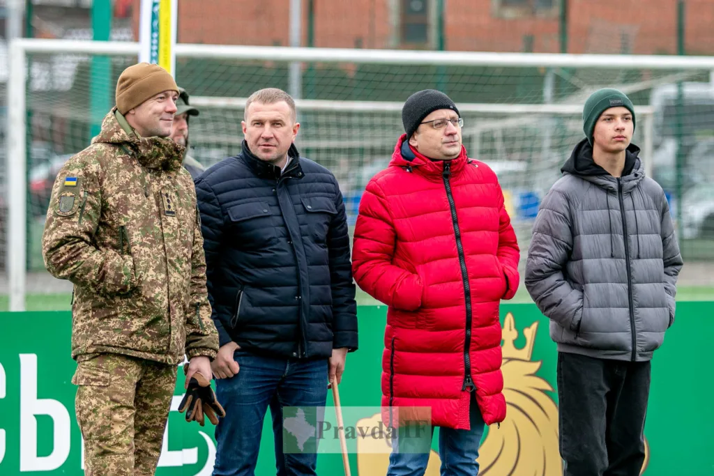 Четверо чоловіків стоять біля футбольного поля