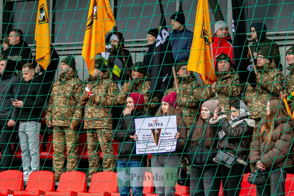 Військові та цивільні тримають прапори на трибуні