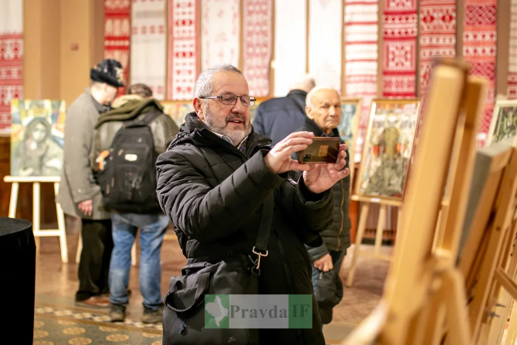 Чоловік фотографує картини на художній виставці
