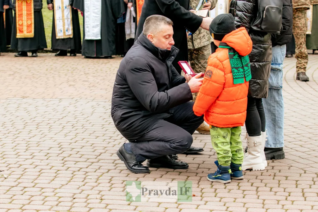 Чоловік вручає медаль дитині на вулиці