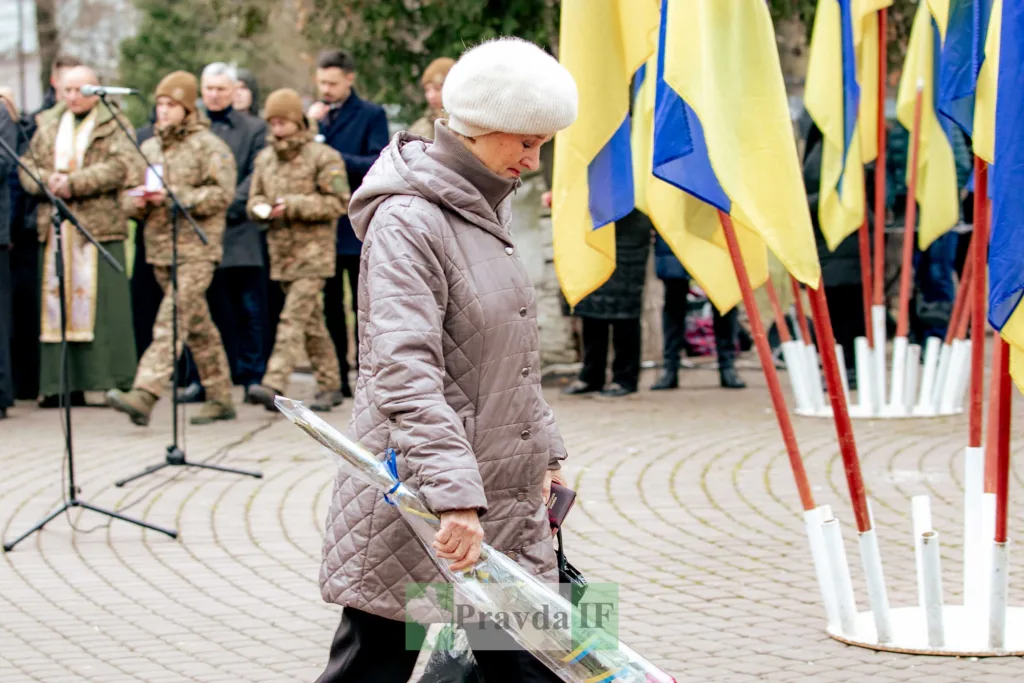 Жінка з квітами біля українських прапорів