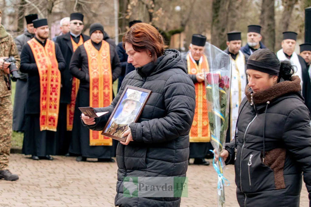 Жінки з фото та квітами на похороні військового