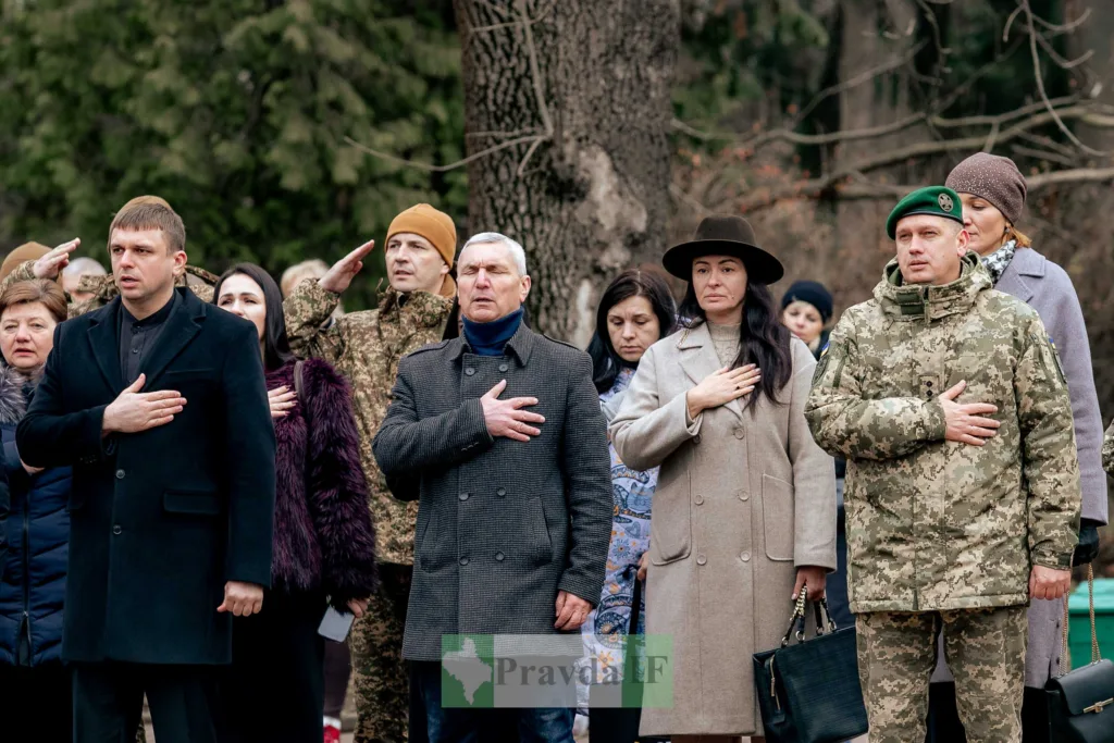 Люди стоять на церемонії, тримаючи руку на серці