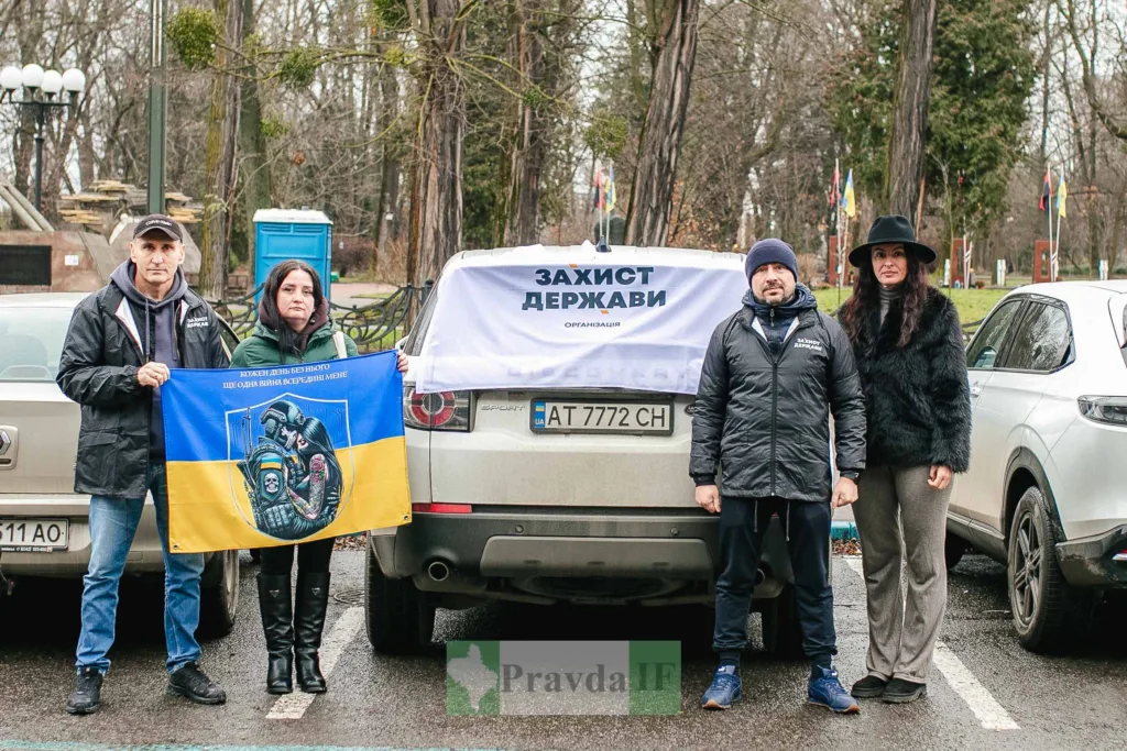 Люди тримають прапори України біля автомобілів