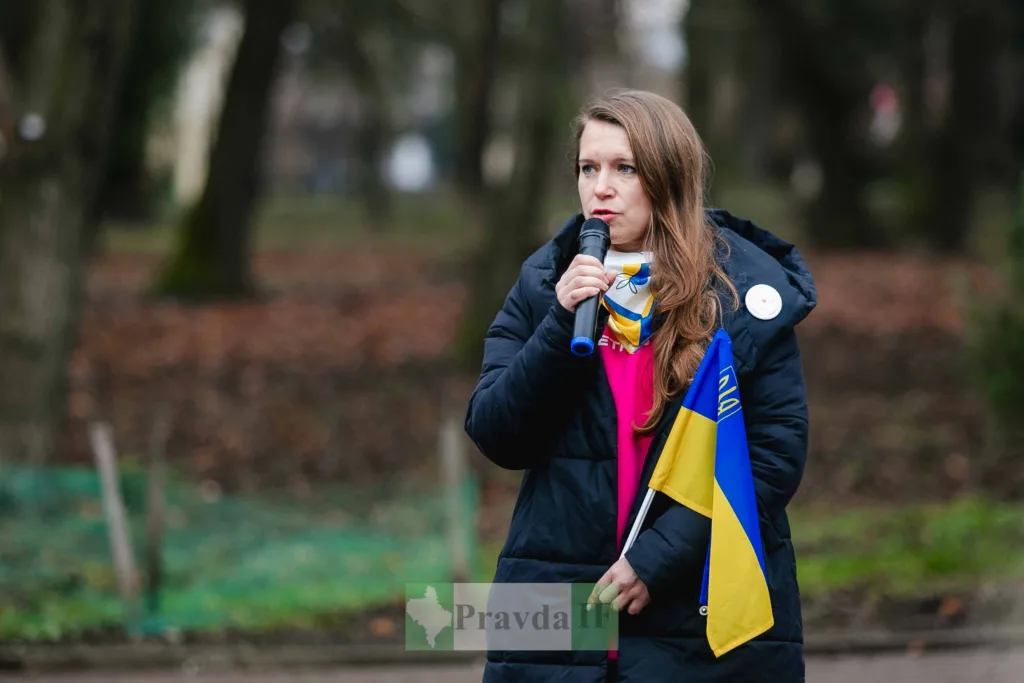 Жінка говорить з мікрофоном та прапором України