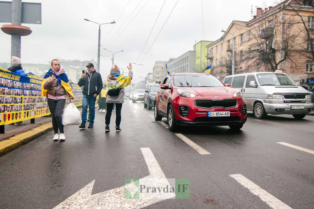 Люди з українськими прапорами на міській вулиці