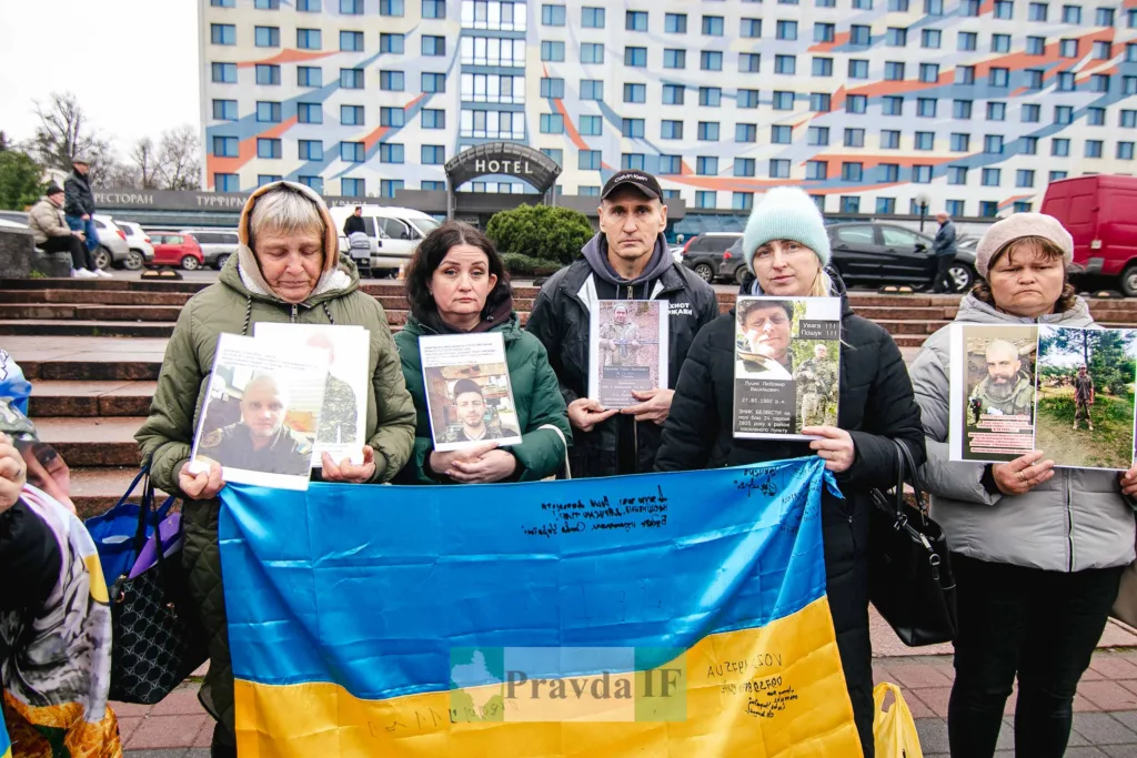 Родичі зниклих військових тримають фото та прапор України