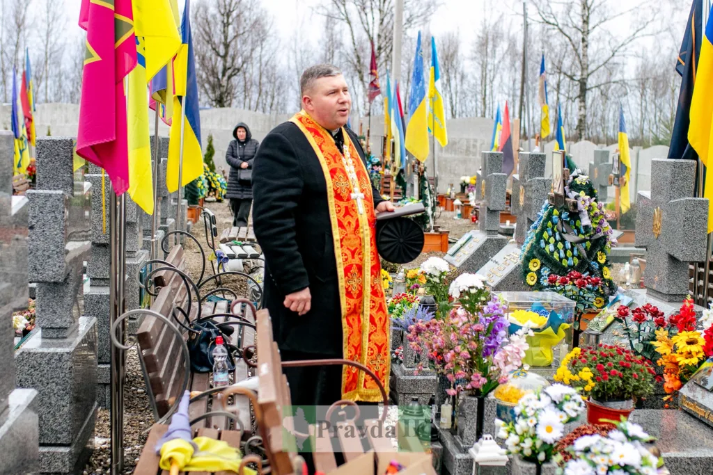 Священник проводить панахиду на військовому цвинтарі