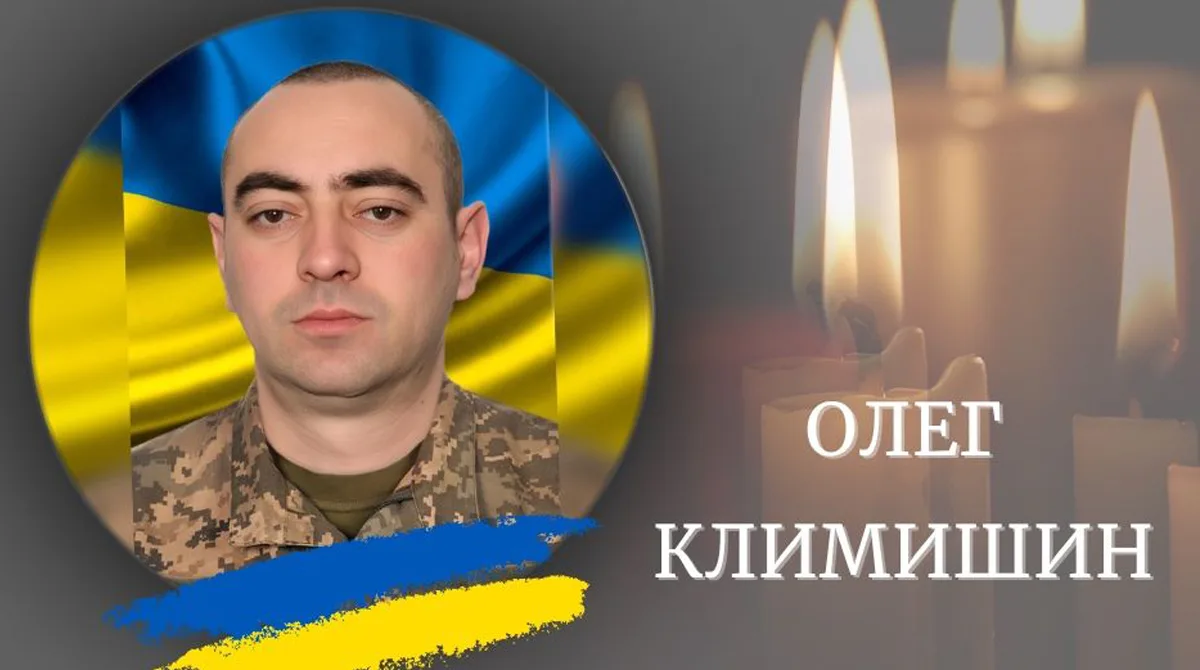 Український військовий на тлі прапора та свічок