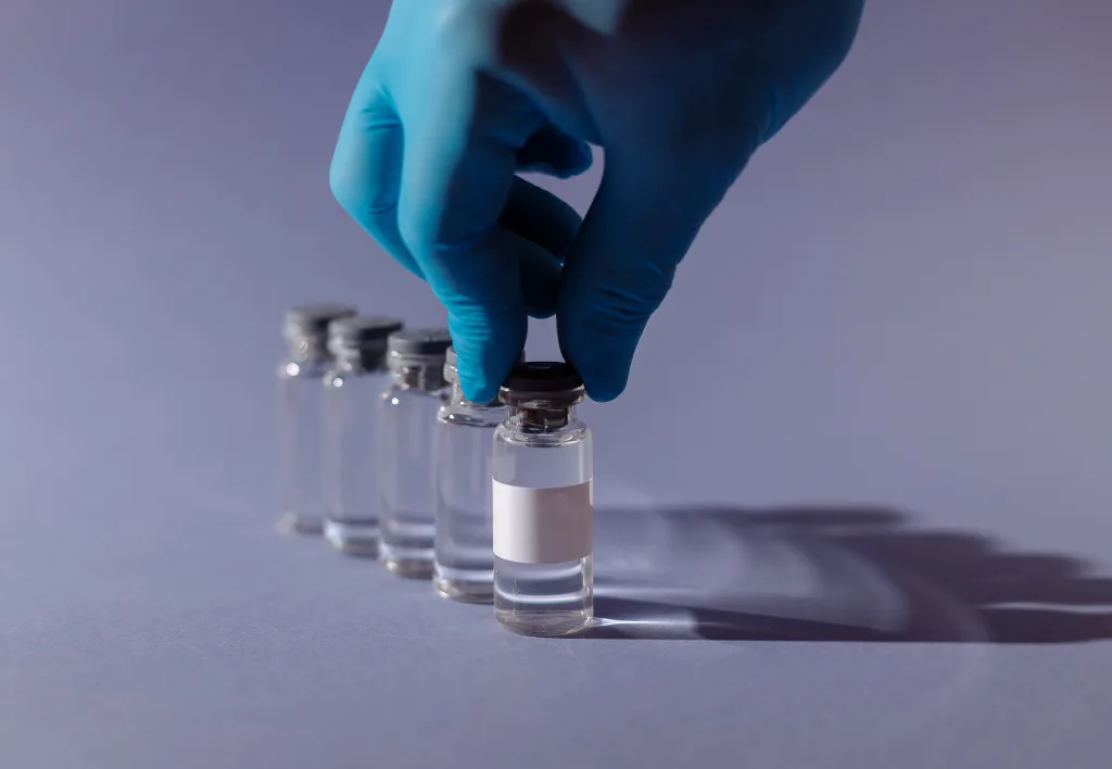 Рука в рукавичці тримає флакон з вакциною
