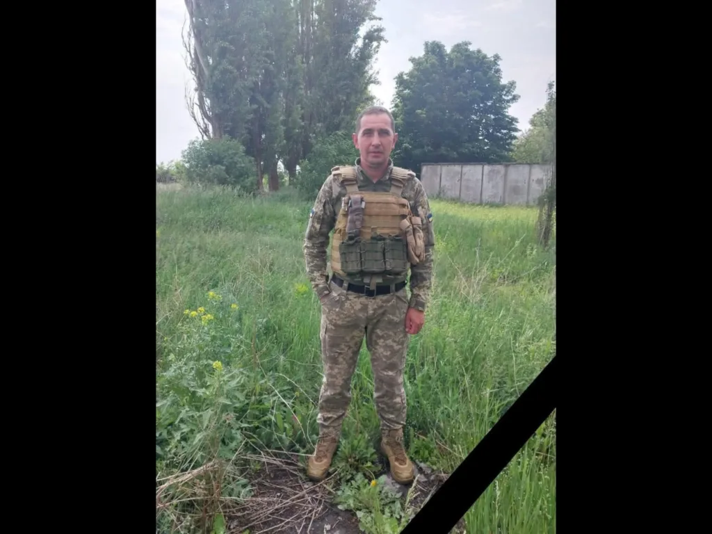 Військовий у камуфляжі стоїть на трав'яному полі