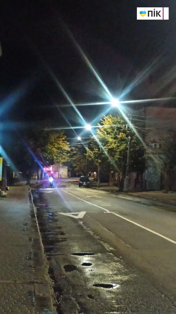 Нічна вулиця з ліхтарями та мокрим асфальтом