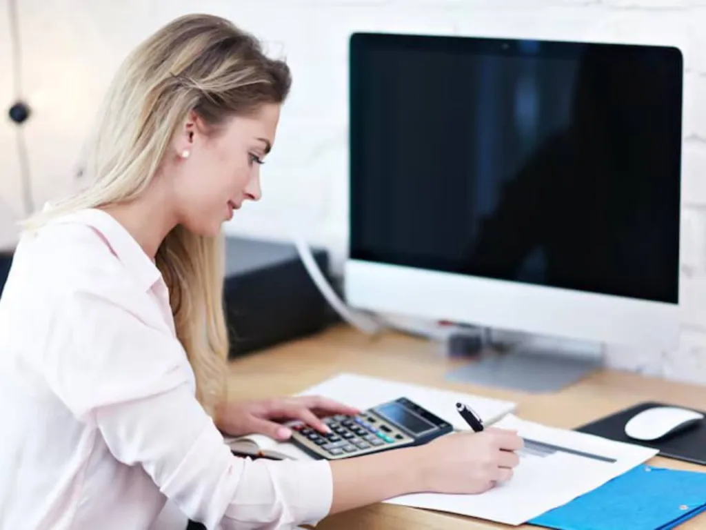Жінка працює за комп'ютером і калькулятором