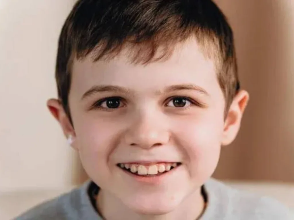 Усміхнений хлопчик дивиться в камеру