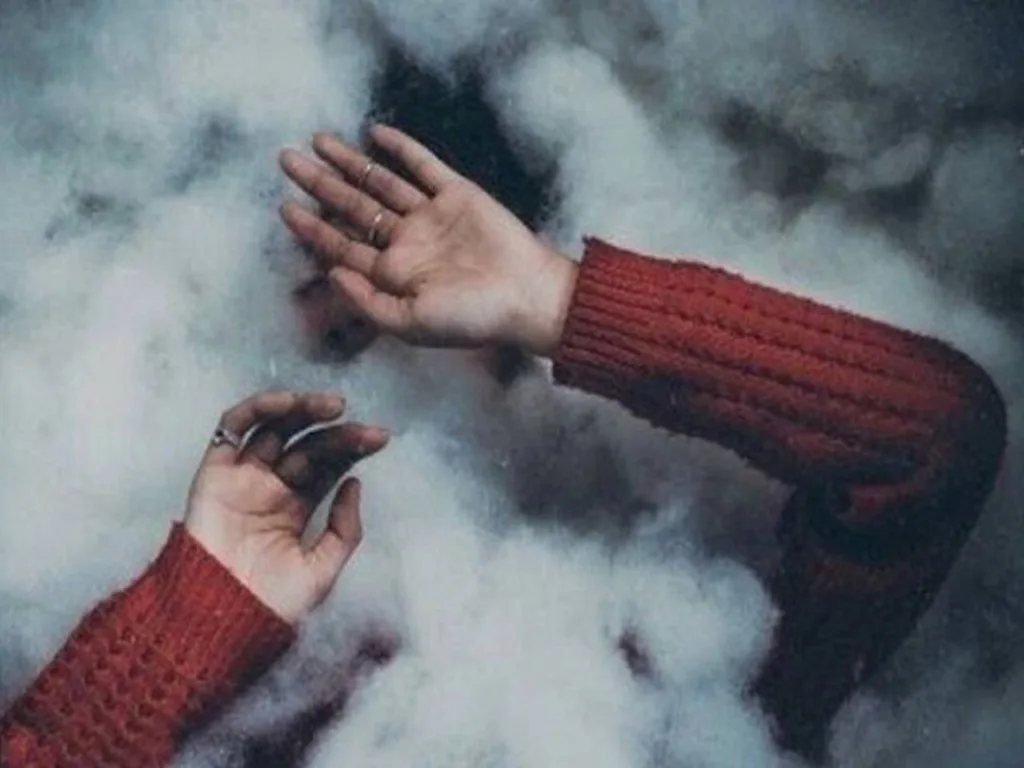 Руки в червоному светрі серед диму