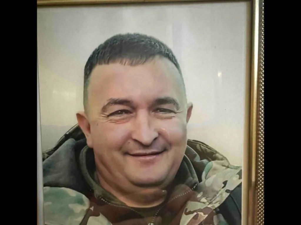 Чоловік у камуфляжі посміхається перед камерою