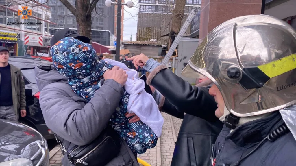 Рятувальник допомагає тримати дитину під час евакуації