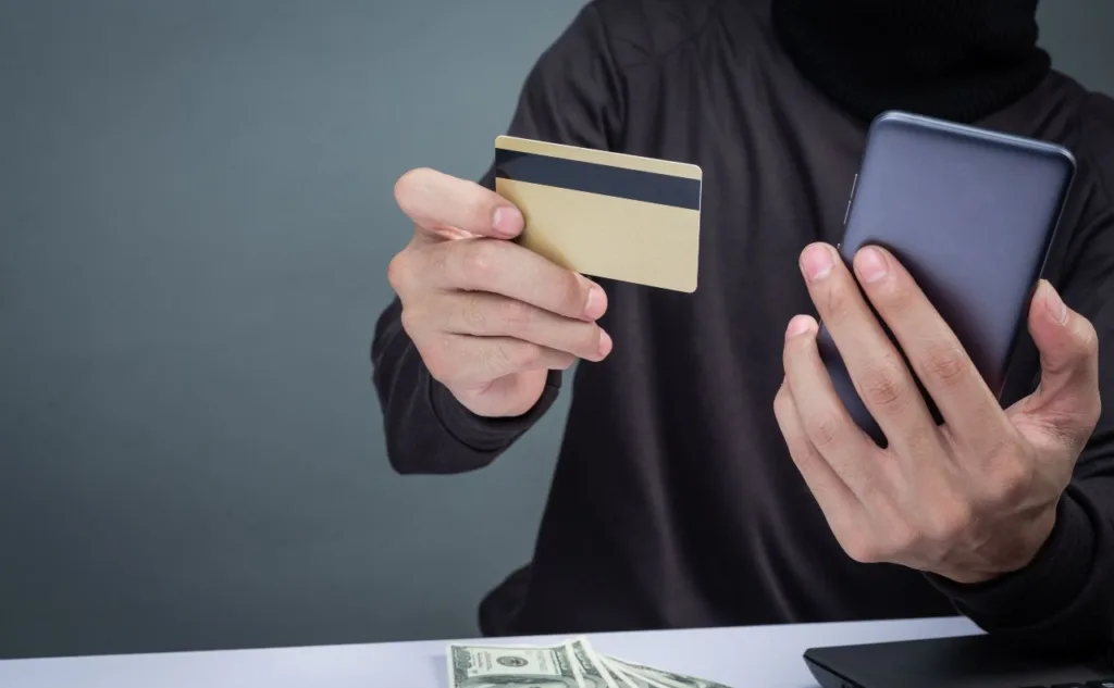 Людина тримає банківську картку та смартфон