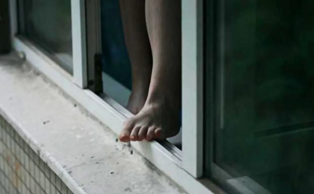 Ноги людини стоять на підвіконні відкритого вікна