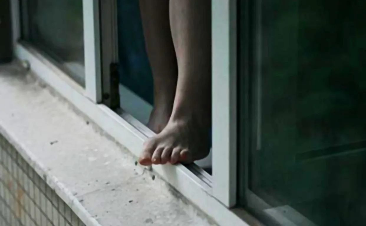 Ноги людини стоять на підвіконні відкритого вікна