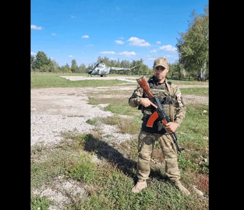 Військовий стоїть з автоматом біля гелікоптера