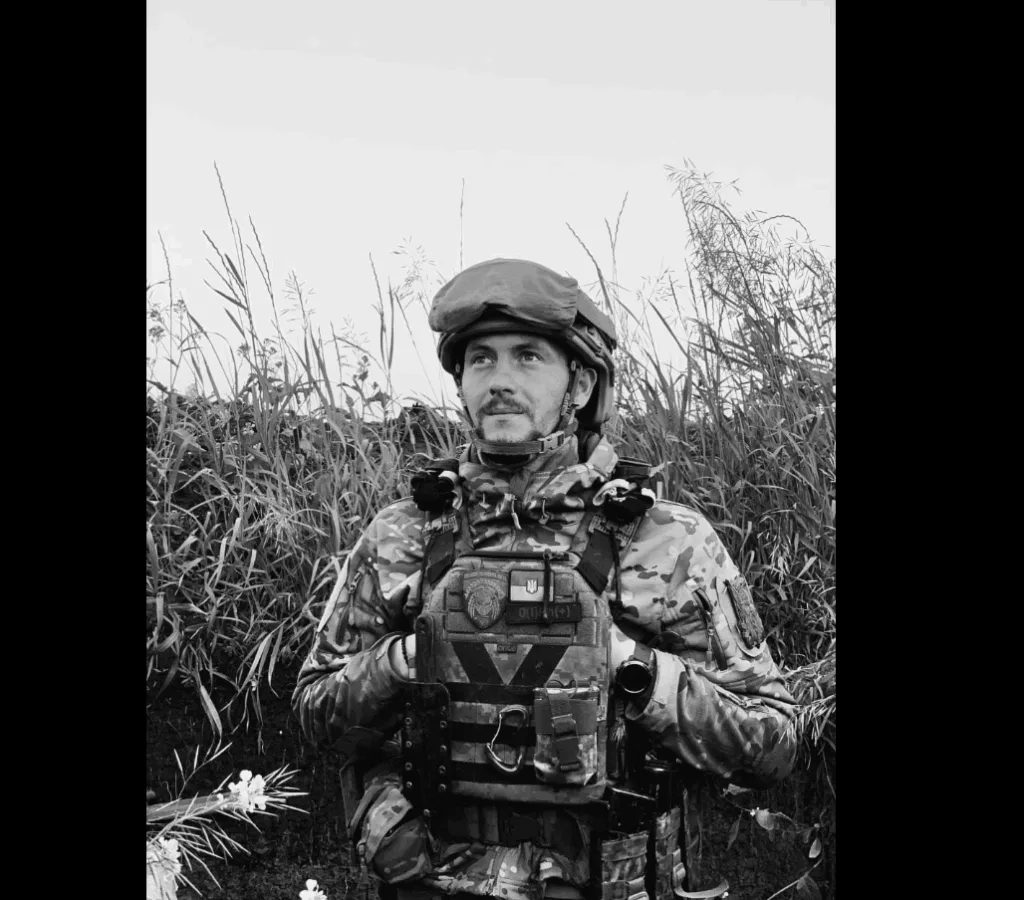 Військовий у камуфляжі стоїть серед трави