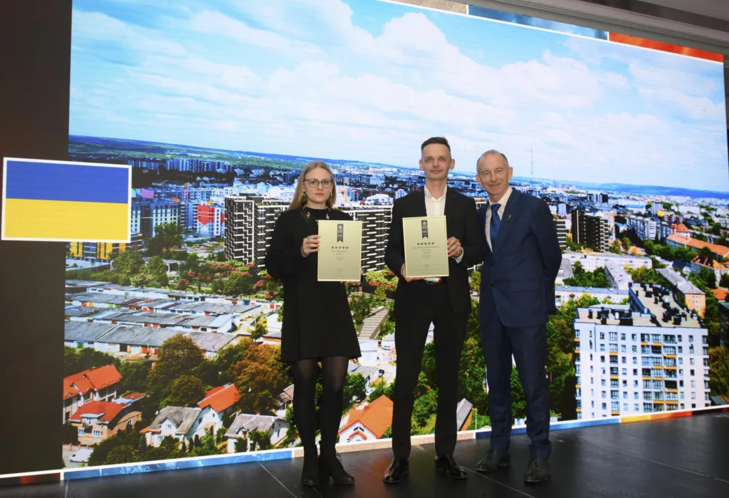 Люди отримують нагороди на сцені з прапором України