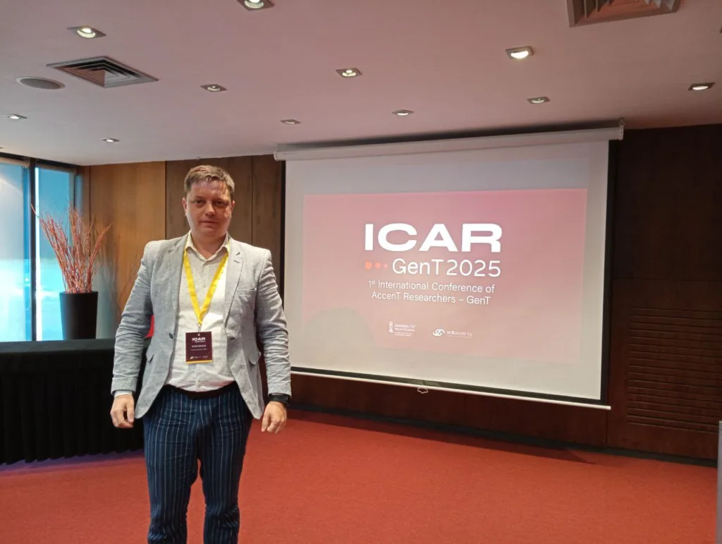 Учасник конференції ICAR GenT2025 стоїть перед екраном