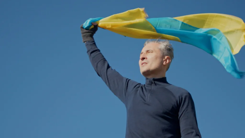 Чоловік тримає прапор України під синім небом