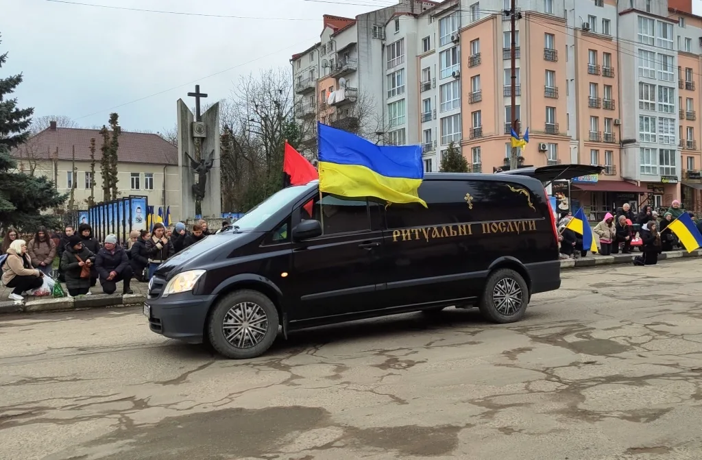 Катафалк з українським прапором на міській вулиці