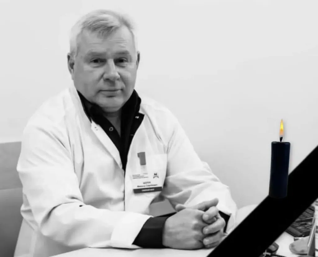 Лікар у білому халаті поруч із запаленою свічкою