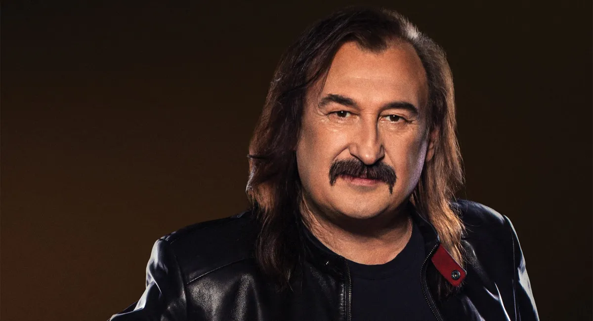 Чоловік з вусами у шкірянці на темному тлі