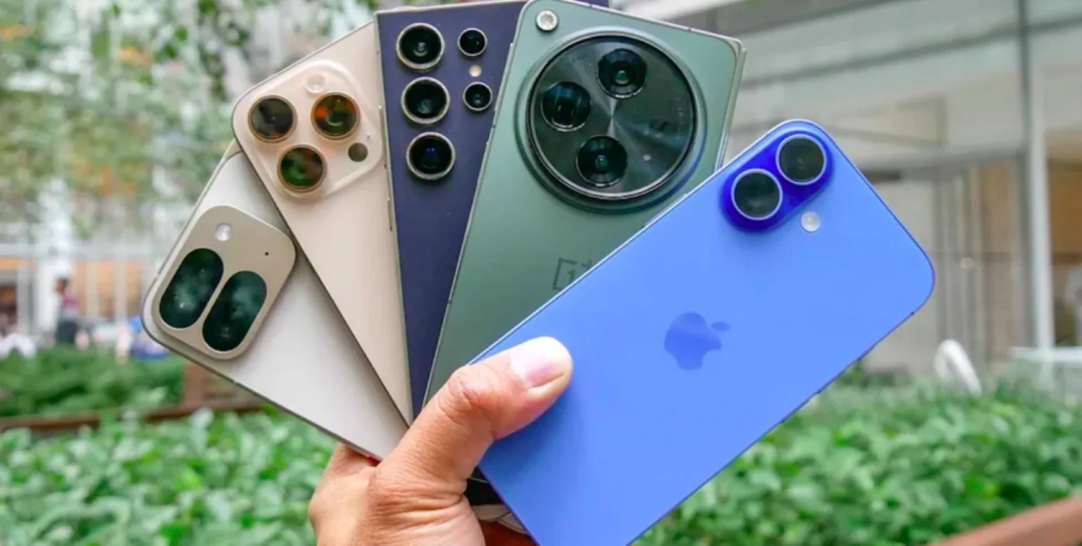 Рука тримає кілька сучасних смартфонів різних кольорів