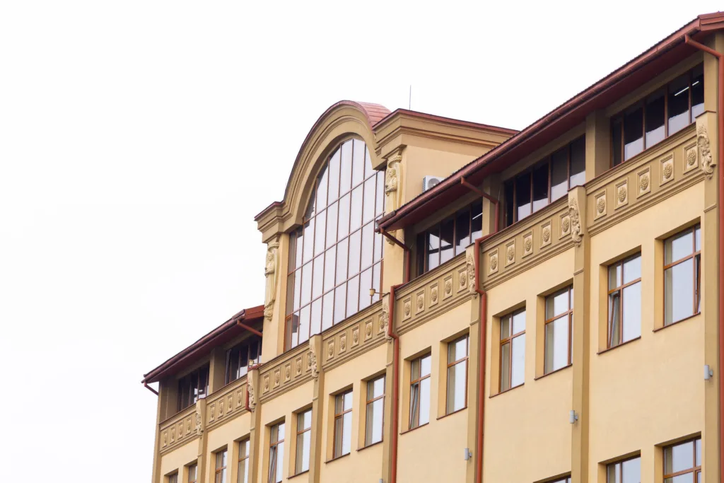 Фасад жовтої будівлі з великими вікнами