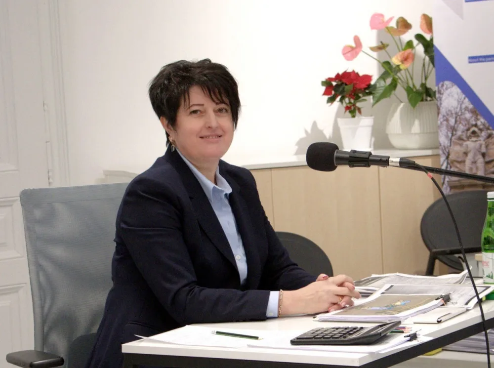 Жінка сидить за столом із мікрофоном