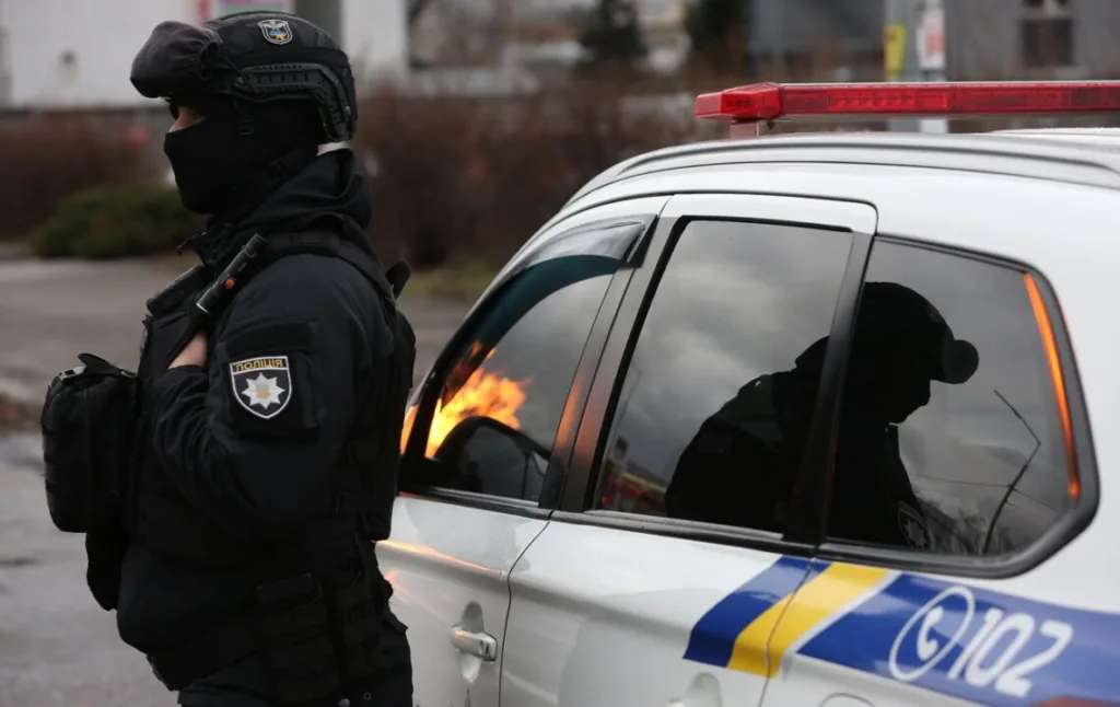 Озброєний поліцейський біля патрульного автомобіля