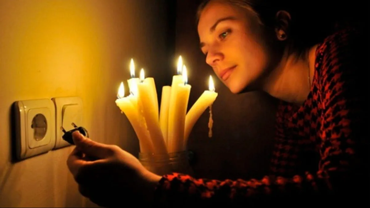Жінка запалює свічки під час відключення електрики