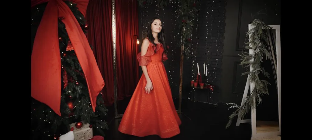 Дівчина у червоній сукні біля різдвяної ялинки