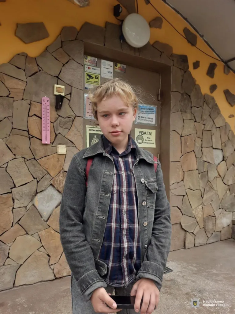 Підліток стоїть біля кам'яної стіни будівлі