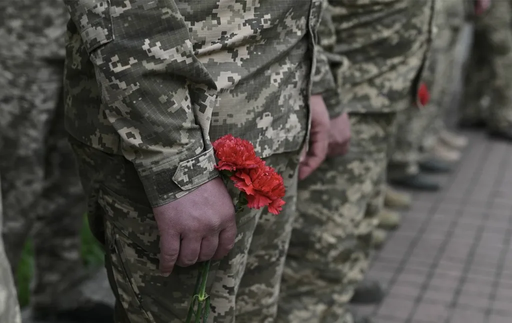 Військові у формі тримають червоні гвоздики