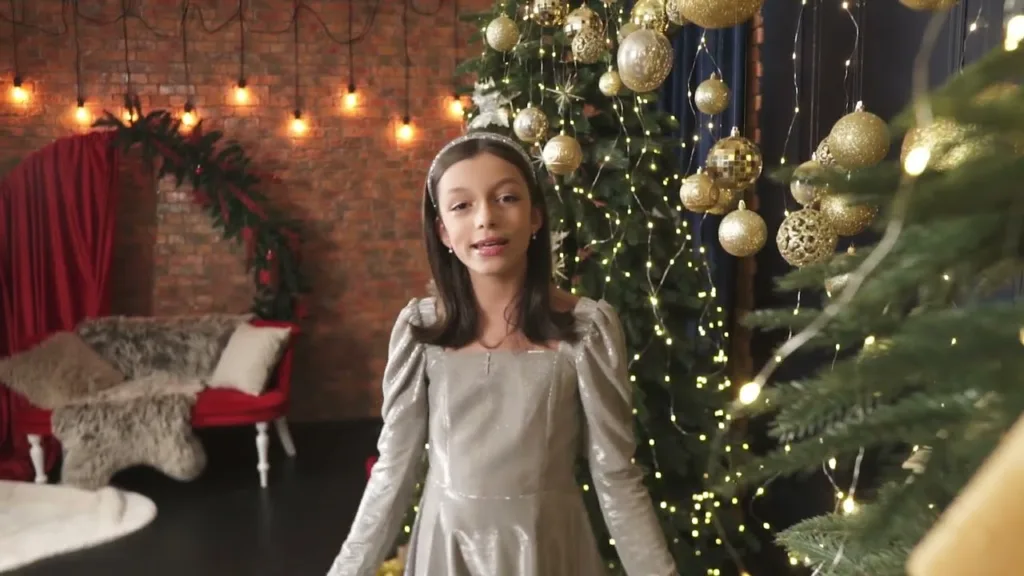 Дівчина біля новорічної ялинки з вогниками