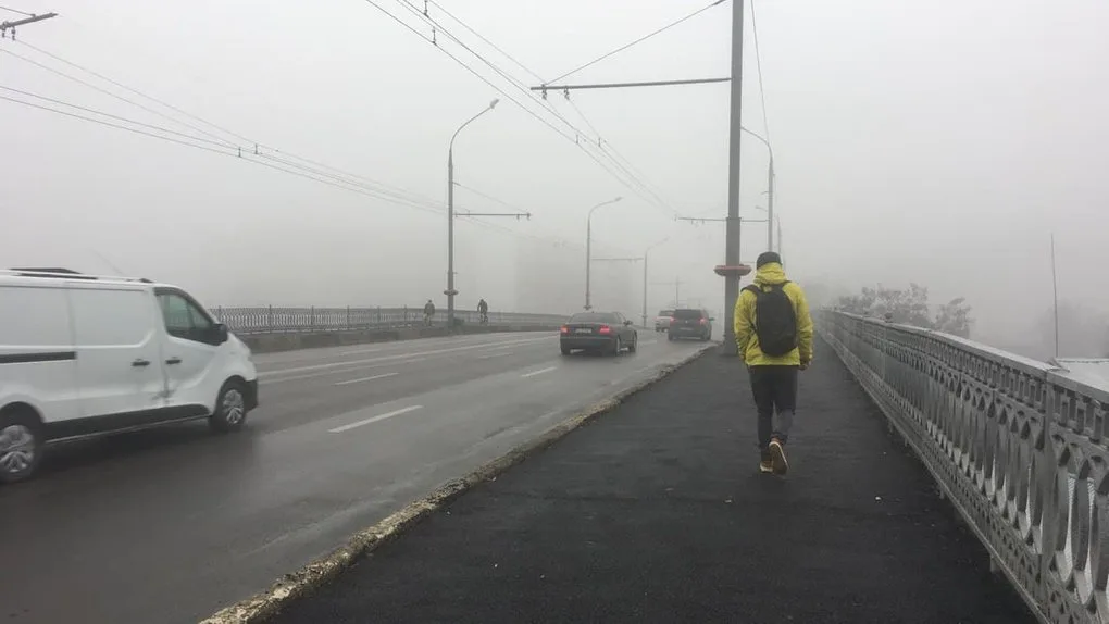 Людина йде туманним мостом уздовж дороги