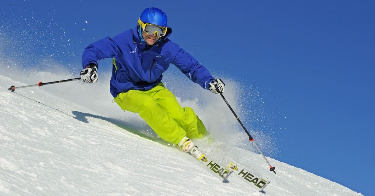 Лижник спускається засніженим схилом під яскравим сонцем