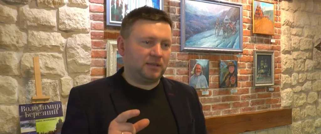Чоловік говорить на фоні виставки живопису