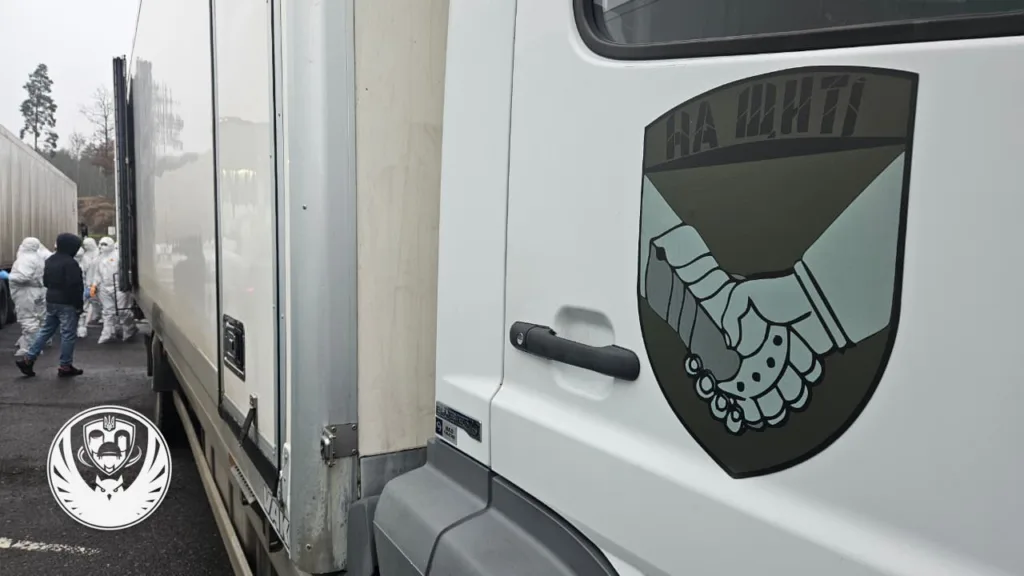 Вантажівка з логотипом та людьми в захисних костюмах