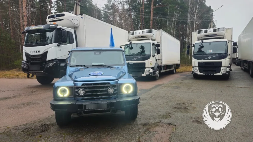 Вантажівки та позашляховик на парковці серед лісу