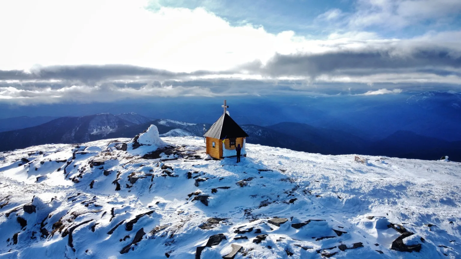 Дерев'яна каплиця на засніженій гірській вершині