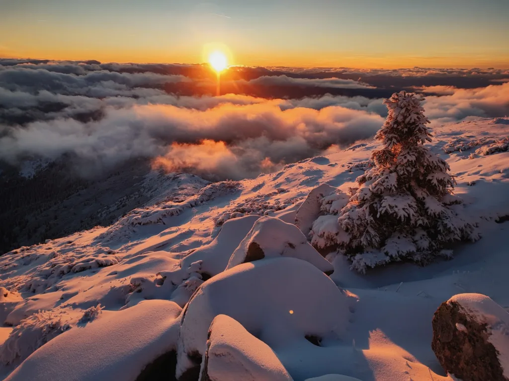 Захід сонця над засніженими горами та хмарами